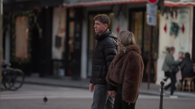 A couple walks hand-in-hand down a street in Paris France The man and woman are enjoying a romantic date in the city strolling past shops and cafes on a sunny.