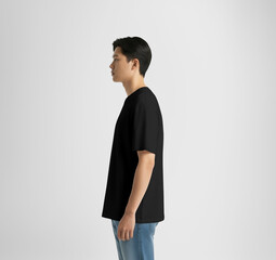 Mockup of black oversized t-shirt on Korean guy in blue jeans, side view, isolated on background. AI generation.