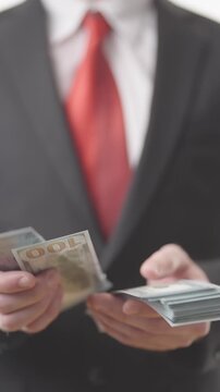 Headless businessman in suit counting a pack of money