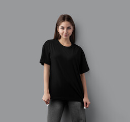 Template of a black oversized t-shirt with a round neckline, on a girl in gray jeans, front view, isolated on a background.