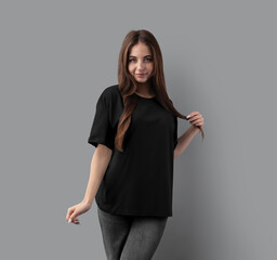 Mockup of a fashionable black oversized t-shirt on a posing girl, front view, for design, branding.