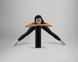 Template of black rolled up floor mat, posing trainer in top, leggings, front view, isolated on background.