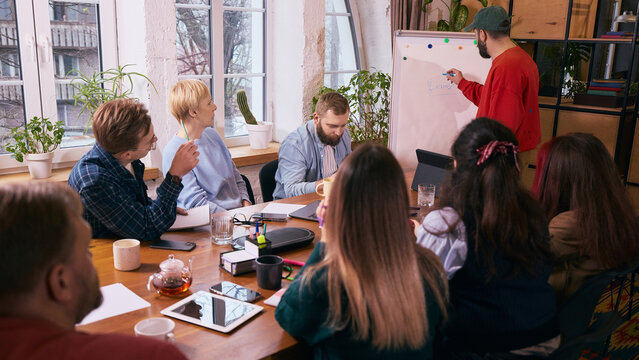 Business team meeting around table in modern office. Concept of internal team discussion, workplace communication and coordination during everyday business meeting.