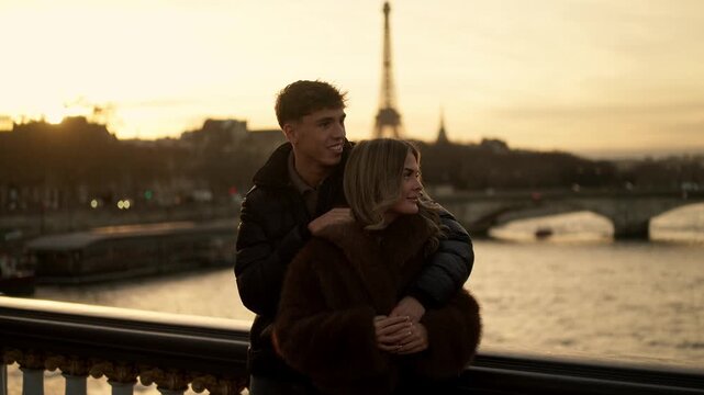 A romantic couple embraces with the Eiffel Tower in the background in Paris France at sunset The golden hour light creates a warm and loving atmosphere The scene captures love affection and the beauty