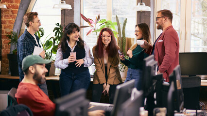 Informal office meeting with diverse team in modern workspace. Concept of inclusive modern office, cross functional collaboration, internal communication, team alignment.