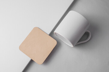 Obraz premium Wooden square coaster and ceramic cup on light background