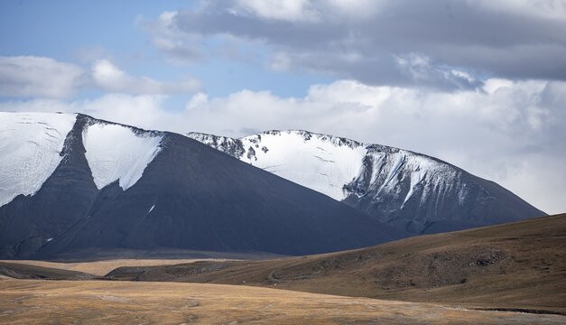 Autumnal plateau with brown grass, glaciated and snow-covered peaks, Ak Shyrak Mountains, near the Kumtor Gold Mine, Tian Shan, Kyrgyzstan