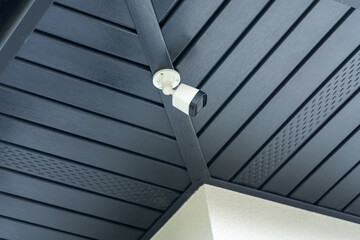 modern, small white camera under the soffit of the roof. Graphite is the dominant color. Security in your own home. Protecting your property and family.
