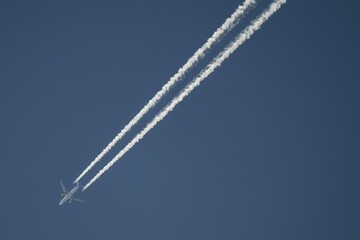 Aeroplane with vapour trail at high altitude, blue sky, Germany
