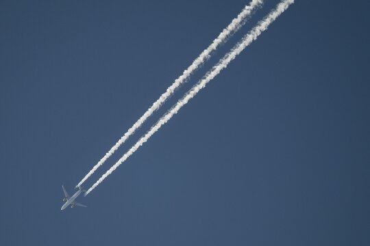 Aeroplane with vapour trail at high altitude, blue sky, Germany