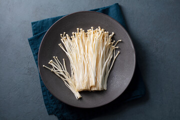 Enoki mushrooms on a black plate. Asian cuisine. Dark grey background. Copy space. Top view.