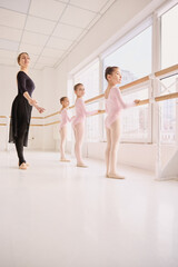 Fototapeta premium Children ballet class focused on posture and physical training. Concept of body alignment development, movement skill education, and youth physical activity use.