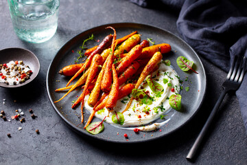 Roasted carrots salad with yogurt. Grey background. Close up.