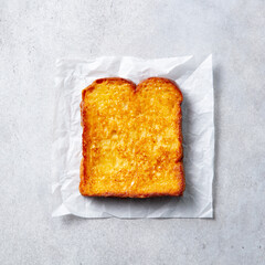 Crispy golden French toast on parchment paper. Grey background. Close up. Top view.
