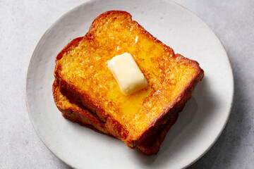 Perfect breakfast delight. Golden French toast slices with melting butter. Grey background. Close up.