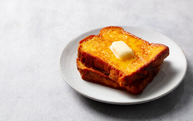 French toast slices with melting butter. Grey background. Close up. Copy space.