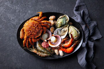Exquisite seafood platter: crab, oysters, scallops, elegant dark backdrop, gourmet dining. Close up. Top view.