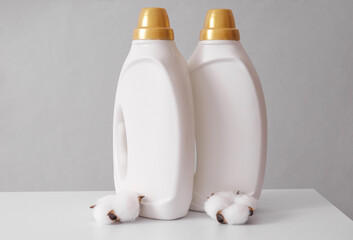 White bottles of washing gel with cotton flowers on a light background