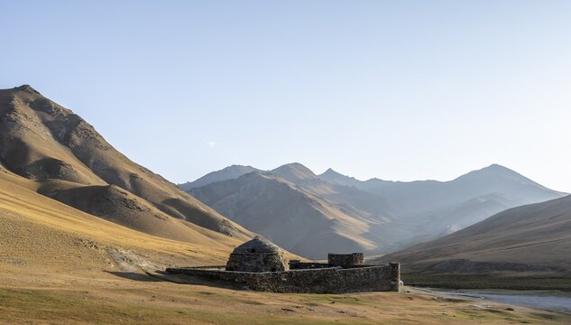 Historic caravanserai Tash Rabat from the 15th century, in the evening light with golden hills, Naryn region, Kyrgyzstan