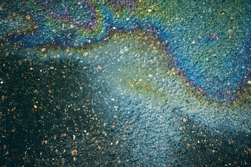 Iridescent oil slick on asphalt, creating a dynamic abstract composition