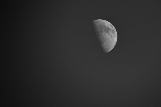 A detailed monochrome moon in a waxing gibbous phase is positioned in the upper right corner of a vast black sky.