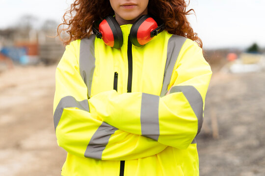 Portrait of femail Construction worker confidently overseeing a building site with equipment and crew members in the background contributing to the project