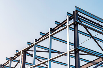 Framework of  modern steel frame building erected against a clear sky during the day showcasing steel construction and architectural design