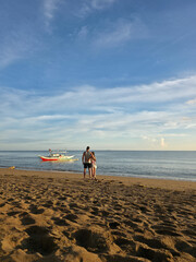 cupple looking at small local boats on turquoise tropical wave sea near philippines islands with beautiful sand beach on morning dawn