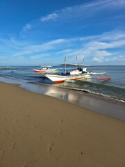 small local boats on turquoise tropical wave sea near philippines islands with beautiful sand beach on morning dawn