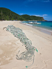 rope on the beautiful sand beach on sunny day near  small local boats on turquoise tropical wave sea near philippines islands