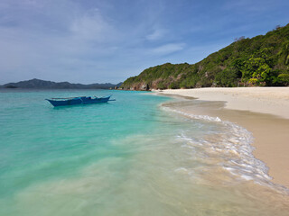 small local boats on turquoise tropical wave sea near philippines islands with beautiful sand beach on sunny day
