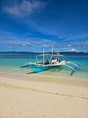 small local boats on turquoise tropical wave sea near philippines islands with beautiful sand beach on sunny day