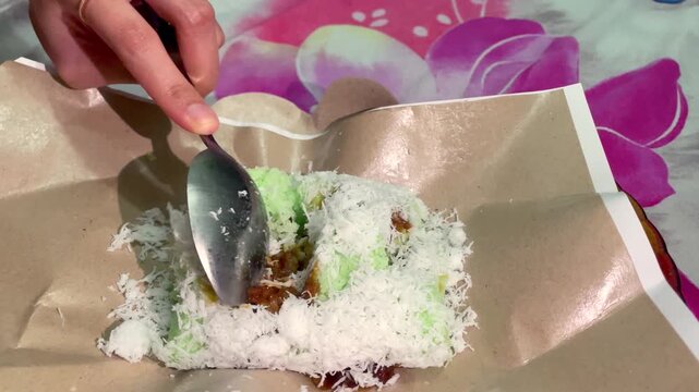 Video close-up slicing putu cake (klepon) with grated coconut and liquid palm sugar