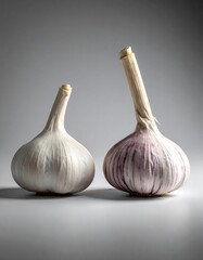 Two garlic bulbs, one white and one purple-striped, on a neutral background