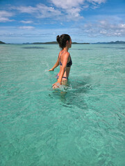 happy young woman in turquoise wave sea in philippines islands on sunny day. asia vocation. vertical