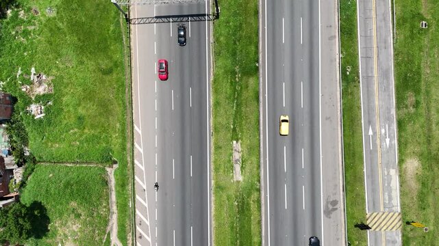 Rodovia vista de cima com ve&iacute;culos em circula&ccedil;&atilde;o organizada, representando mobilidade regional, efici&ecirc;ncia do sistema vi&aacute;rio e a import&acirc;ncia do transporte rodovi&aacute;rio.