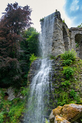 Tranquil Waterfall With Lush Surroundings, Serene Waterfall Flowing Beneath Stone Bridge Amidst Vibrant Woods