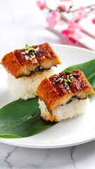 Two pieces of grilled eel sushi on a white plate