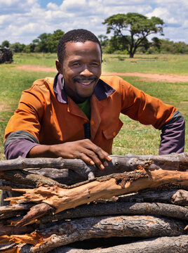 young african man in the village standing in front of a pile of firewood , deforestation, rural development and community projects