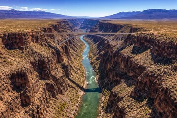 Spectacular aerial view of the Grand Canyon with a bridge spanning the deep canyon and Colorado River flowing below under clear blue skies