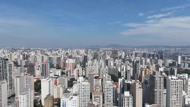 Vis&atilde;o ampla do centro urbano de S&atilde;o Paulo com pr&eacute;dios e arranha c&eacute;us, representando a dimens&atilde;o metropolitana, o desenvolvimento econ&ocirc;mico e a intensa ocupa&ccedil;&atilde;o urbana.