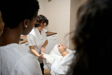 Esthetician tutor teaching students skin care procedure