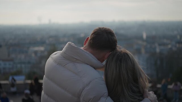 A romantic couple embraces with the Paris city skyline in the background The man and woman are in love enjoying the view of Paris France The clip features slow motion.