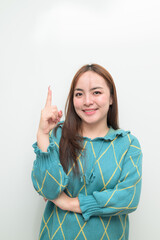 Portrait of a young Asian woman pointing finger against white background