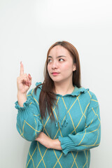 Portrait of a young Asian woman pointing finger against white background
