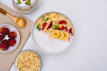 Deliciously prepared bowl of oatmeal topped with fresh banana slices, bright red strawberries, and vibrant kiwi pieces, showcasing a healthy breakfast.