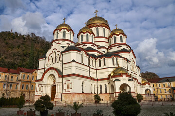 Fototapeta premium Sunny close-up of the main temple of New Athos Monastery under a blue sky. Bright daylight highlights Orthodox architecture, golden domes and historic spiritual heritage of Abkhazia.