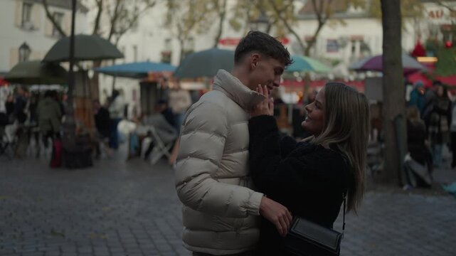 A romantic couple embraces in Montmartre Paris France The man kisses the woman on the cheek in an outdoor setting The scene captures travel love and affection in Europe.