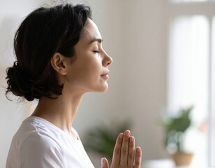 Young woman meditating with eyes closed and hands pressed together in prayer pose