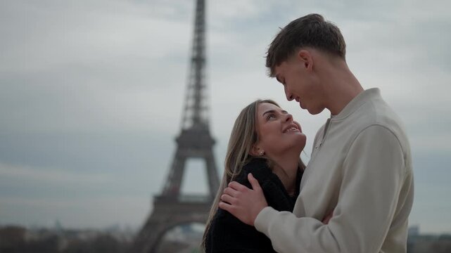 A romantic couple embraces in Paris France with the iconic Eiffel Tower in the background The clip captures a moment of love and connection between the couple highlighting the beauty of Paris as a tra